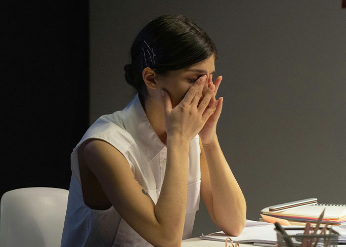 Person in an office covering face with hands, possibly recalling an awkward job interview moment.