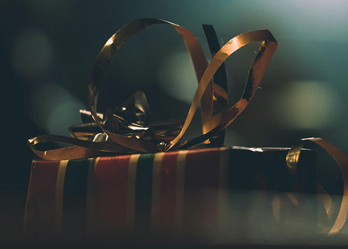 Gift box wrapped with colorful paper and gold ribbons, illustrating unique life hacks for gifting.