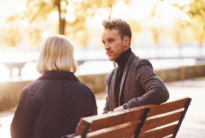 Man and woman on a park bench, the man looking at the woman, highlighting neighbor interaction dynamics.