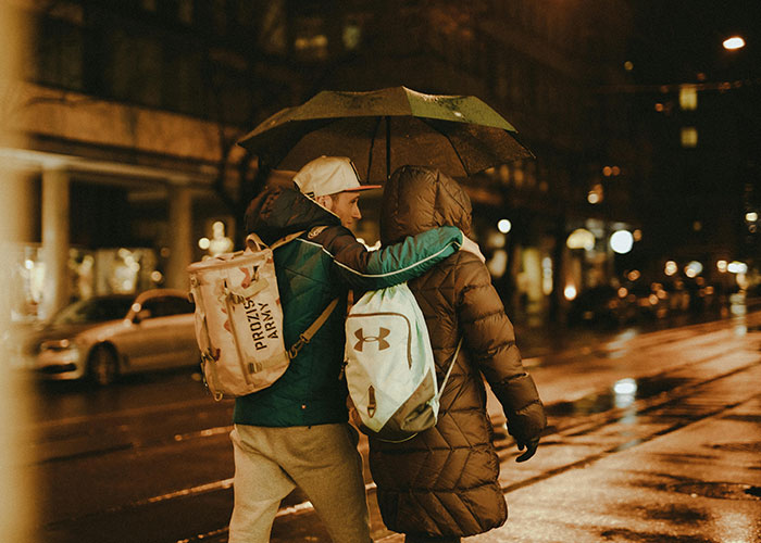 Couple under an umbrella on a rainy night, highlighting a different and thoughtful gesture in the city.