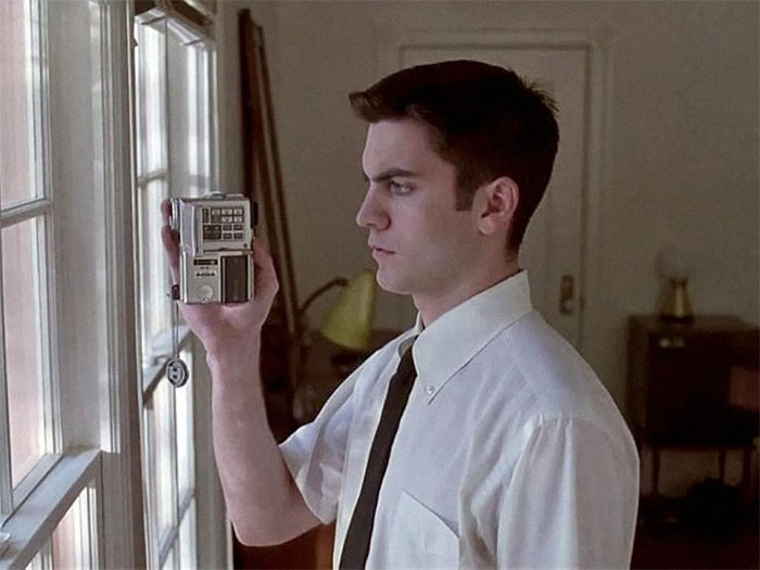 Young man in a white shirt and tie holding a recorder, representing faded celebrity status.