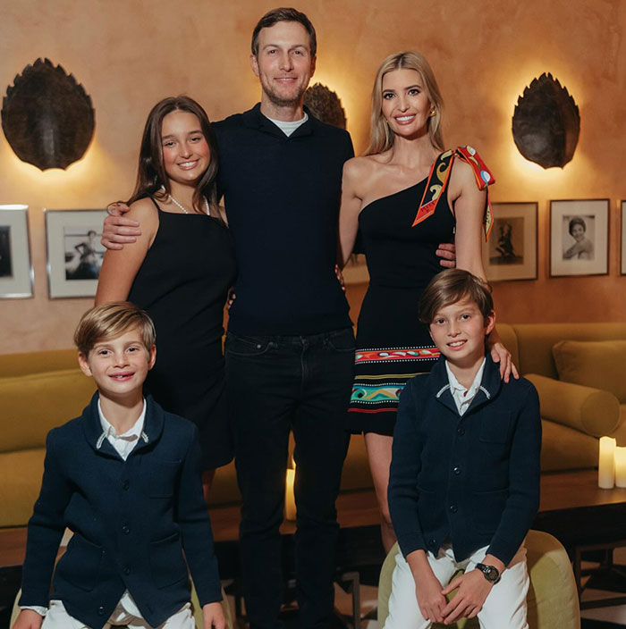 Family posing together in a living room; focus on elegance and class in their attire.