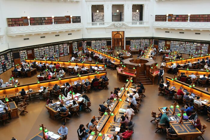 People studying in a large library, symbolizing adult realizations with books and discussions.