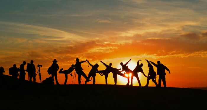Silhouettes of people posing against a vibrant sunset sky, embodying 2000s teens nostalgia.