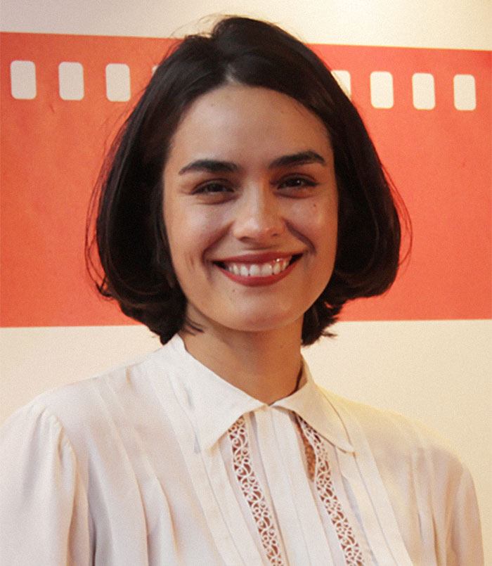 Smiling woman in front of a red backdrop, representing celebrities slowly losing fame.