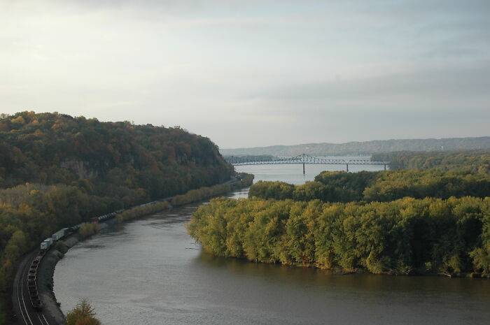 Scenic river and forest view with distant bridge, showcasing amazing views in states.