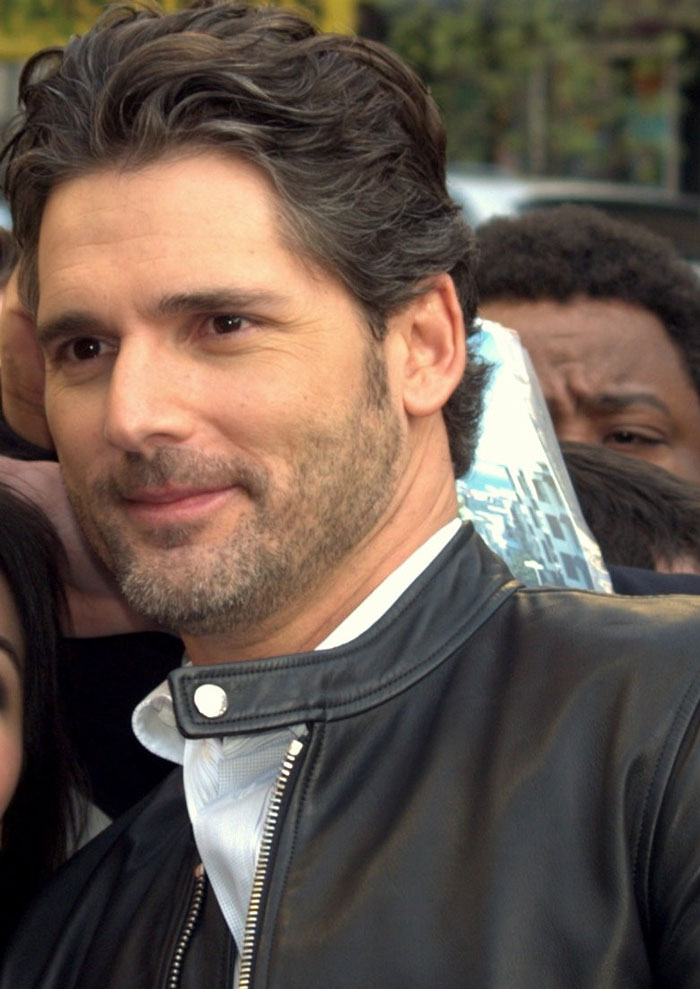 "Man in a leather jacket smiling in a crowd, representing celebrities slowly losing fame."