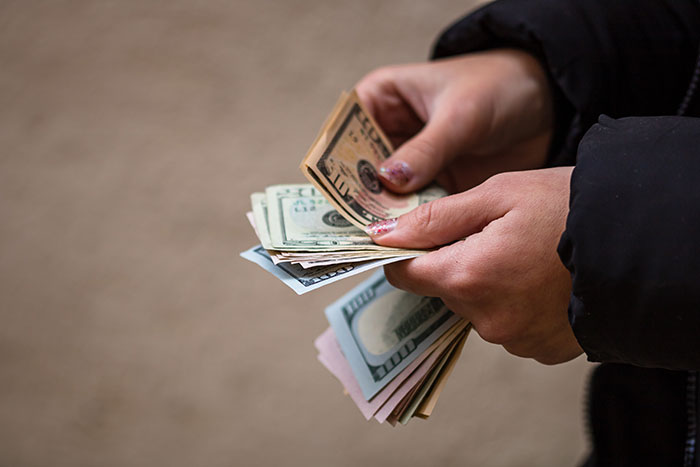 Hands holding a stack of US dollar bills, related to an apartment scam and unexpected revenge. Hands holding a stack of US dollar bills, related to an apartment scam and unexpected revenge.