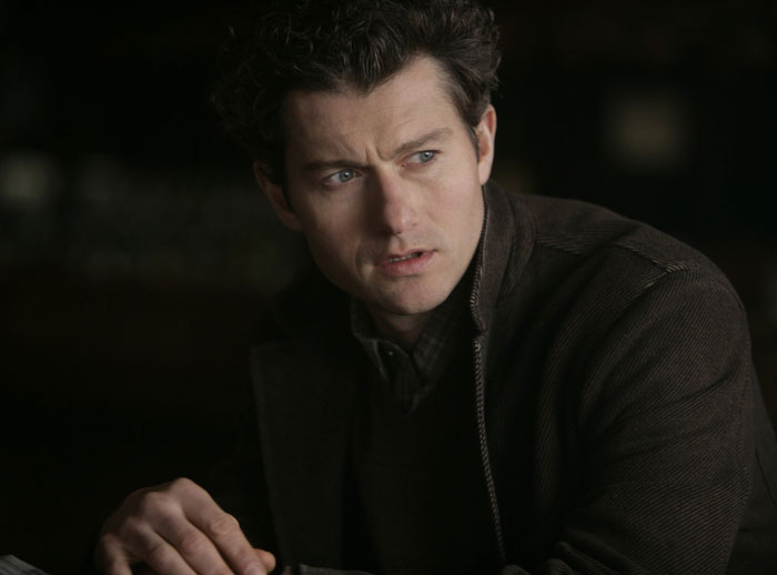 Man in a dark jacket with curly hair sits, representing celebrities who lost their fame.