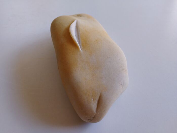 Sculpture resembling a soft stone with a carved detail, showcasing defiance of physical expectations.