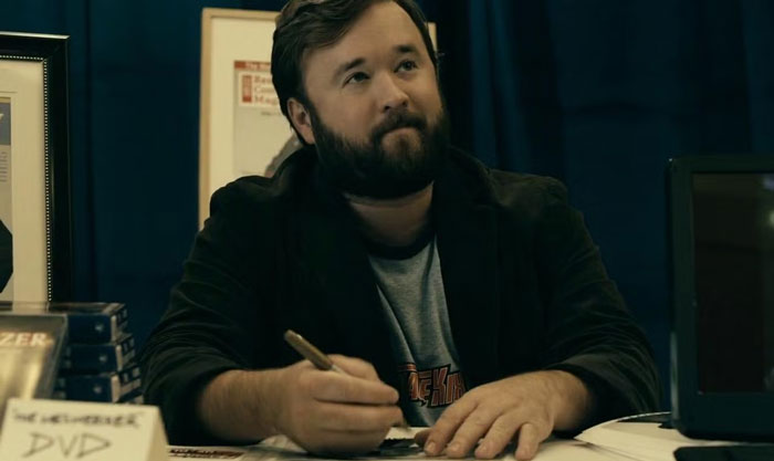 Actor signing autographs at an event booth, highlighting celebrities who lost fame.