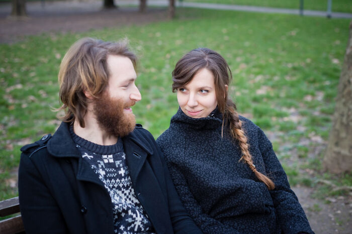 Man and woman sitting on a park bench, engaged in conversation.