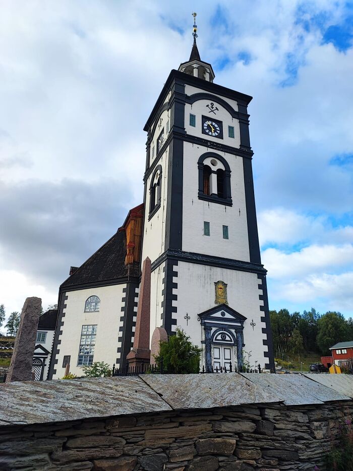 Historic church with a tall tower against a cloudy sky, showcasing fascinating architecture and intricate design details.