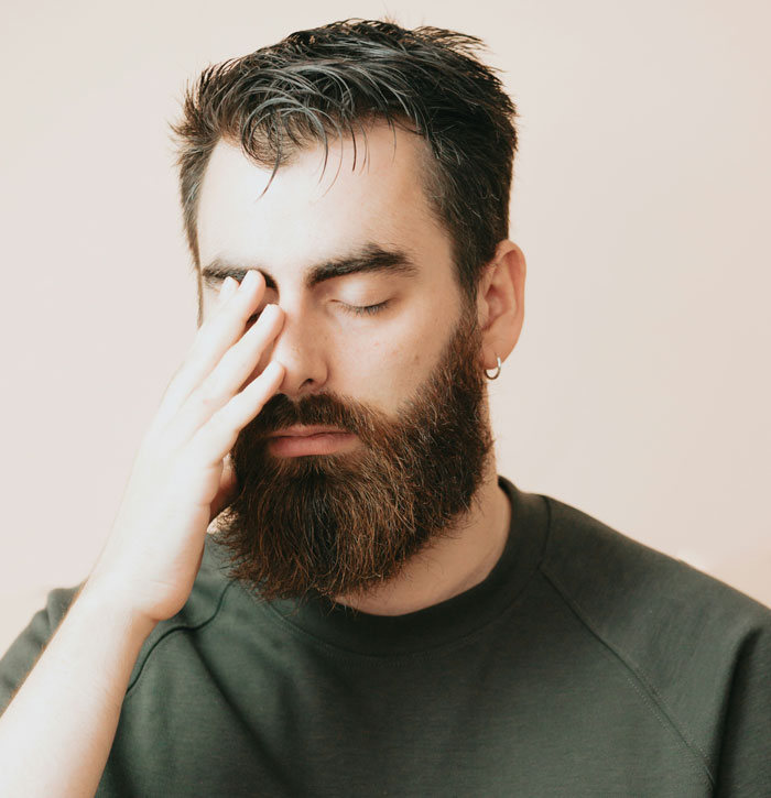 Bearded man with closed eyes, wearing a dark shirt, illustrating 'deadbeat' stereotype challenge in business context.
