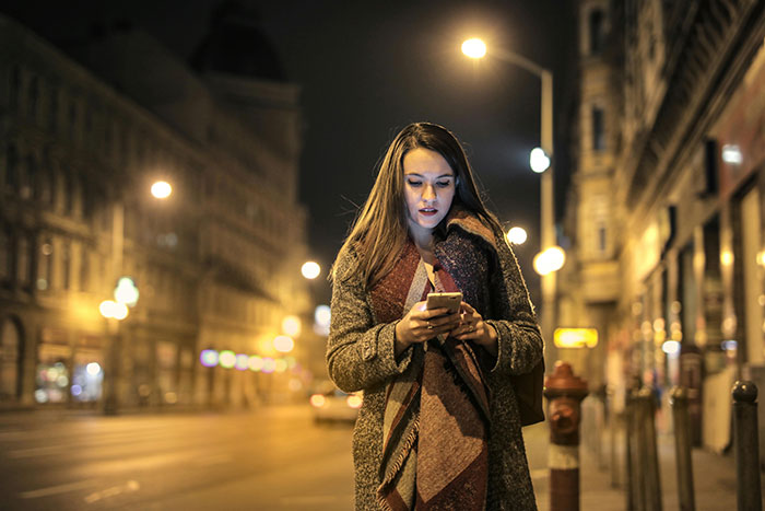 Woman walking at night, looking at her phone, wrapped in a scarf. Keywords: girlfriend, spoiled brat, angry.