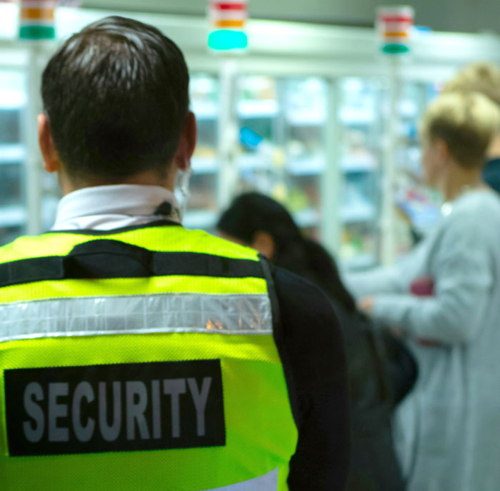 Security guard in a store with blurred background, highlighting mobility carts and disability access concerns.