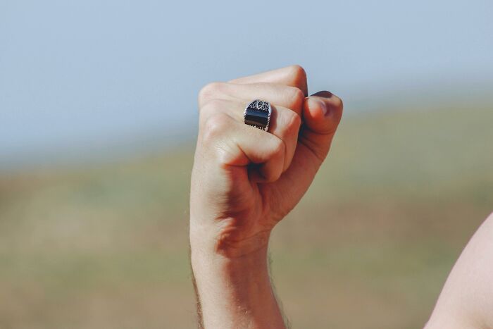 A fist raised in the air, focus on a silver ring, symbolizing teachers' unusual actions at school.