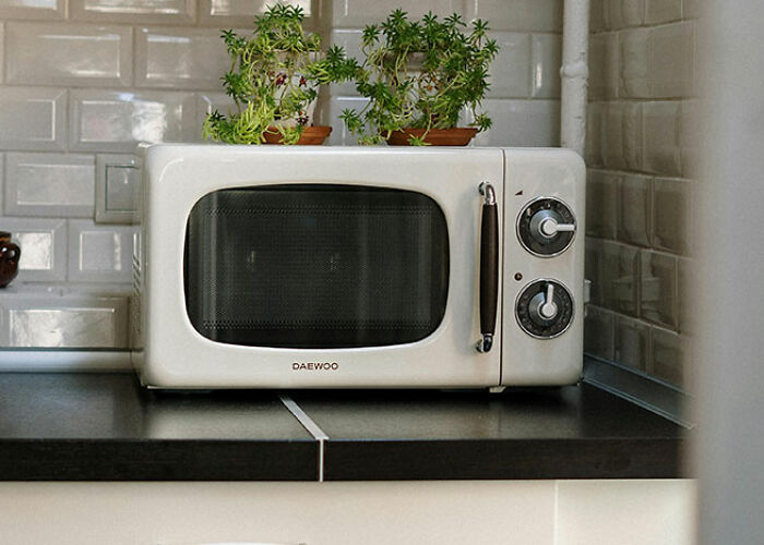 Retro microwave on a kitchen counter with potted plants, showcasing unique life hacks.
