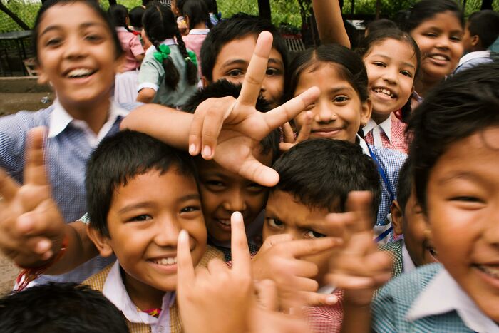 Children smiling and making peace signs, symbolizing innocence before adult realizations.