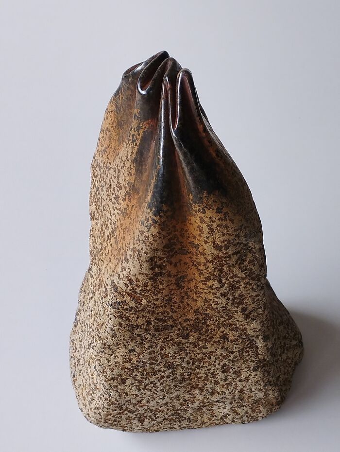 A sculpture resembling a soft, draped fabric, yet made of stone, showcases a unique blend of softness and solidity.