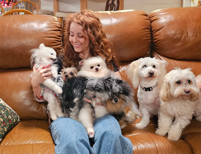 Vanessa De Prophetis on a couch surrounded by happy, fluffy dogs.
