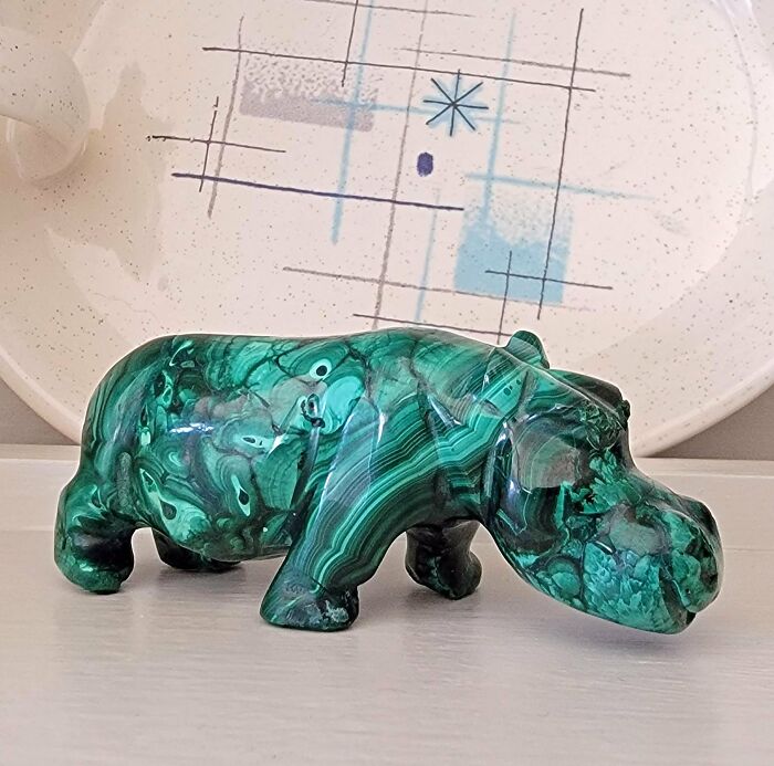 Green stone hippo figurine, a weird and wonderful secondhand find placed in front of a patterned plate.