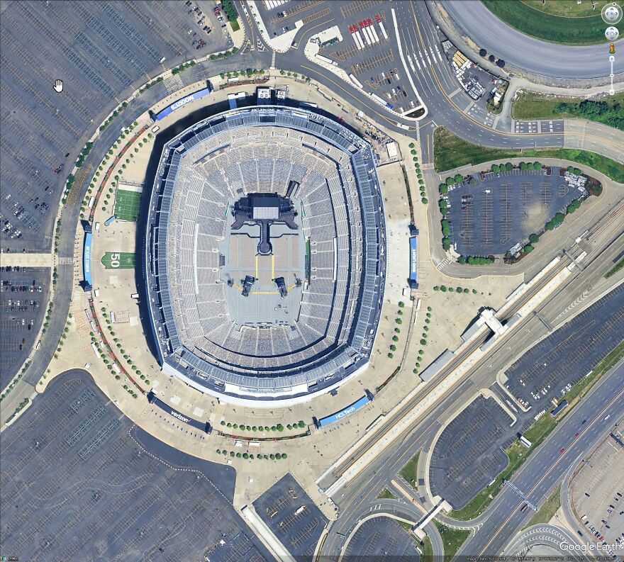 Aerial view of a large stadium found on Google Earth, surrounded by parking lots and roads.
