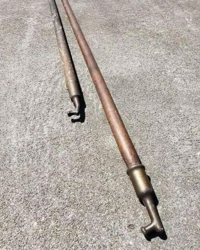 Two old-school items, metallic rods with hooks, lying on a concrete surface.