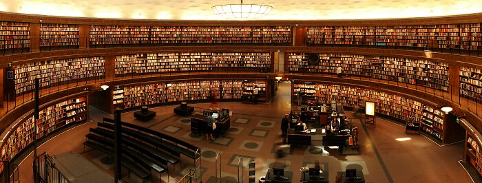 A large, circular library with numerous bookshelves and people studying, capturing a serene academic atmosphere.