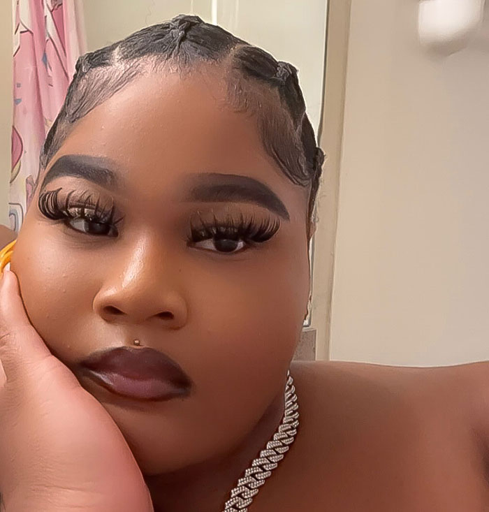 Plus-size woman with braided hair and diamond necklace posing indoors.