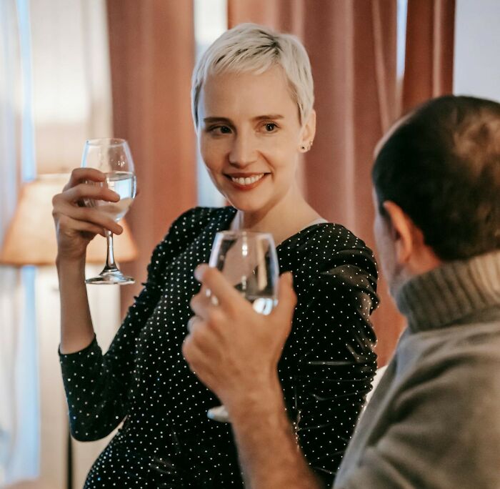Woman and man toasting with wine glasses in a cozy setting, discussing judgment-free activities for men.