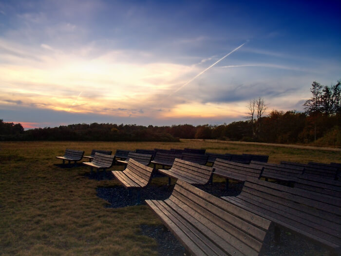 Benches facing a stunning sunset over a scenic field, highlighting amazing views.