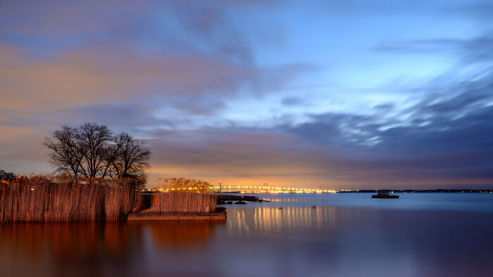 Serene twilight view of a lake with trees and a distant bridge, showcasing amazing views in the states.