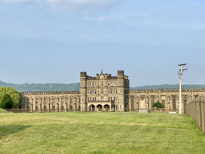 Historic building under blue sky, showcasing amazing views of the states, surrounded by green fields.