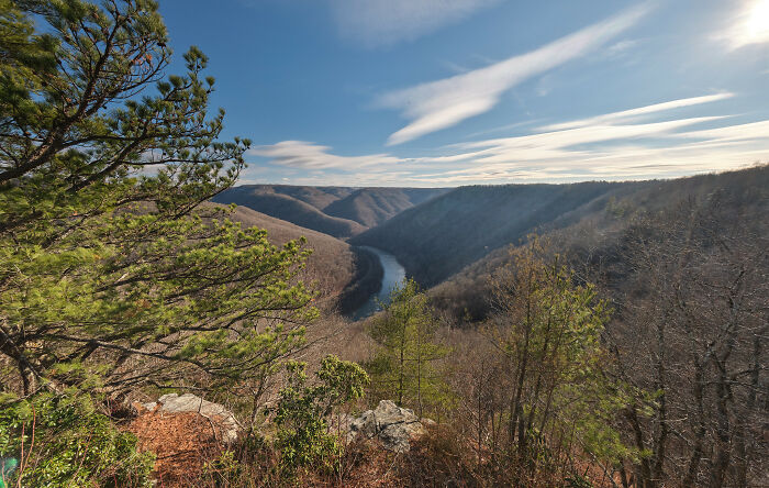 Scenic view of a winding river through lush green hills under a clear blue sky, showcasing amazing views in nature.