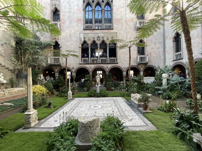 Elegant courtyard with mysterious statues and lush greenery, evoking weird unsolved mysteries.