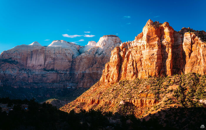 Majestic rock formations with a sunlit canyon and clear blue sky, showcasing amazing views.