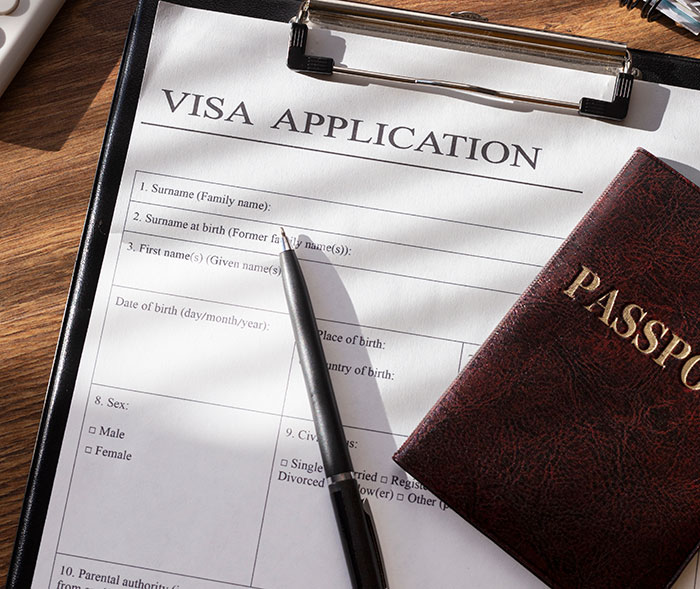 &ldquo;Visa application form and passport on a wooden desk, symbolizing international travel or documentation process.&rdquo;