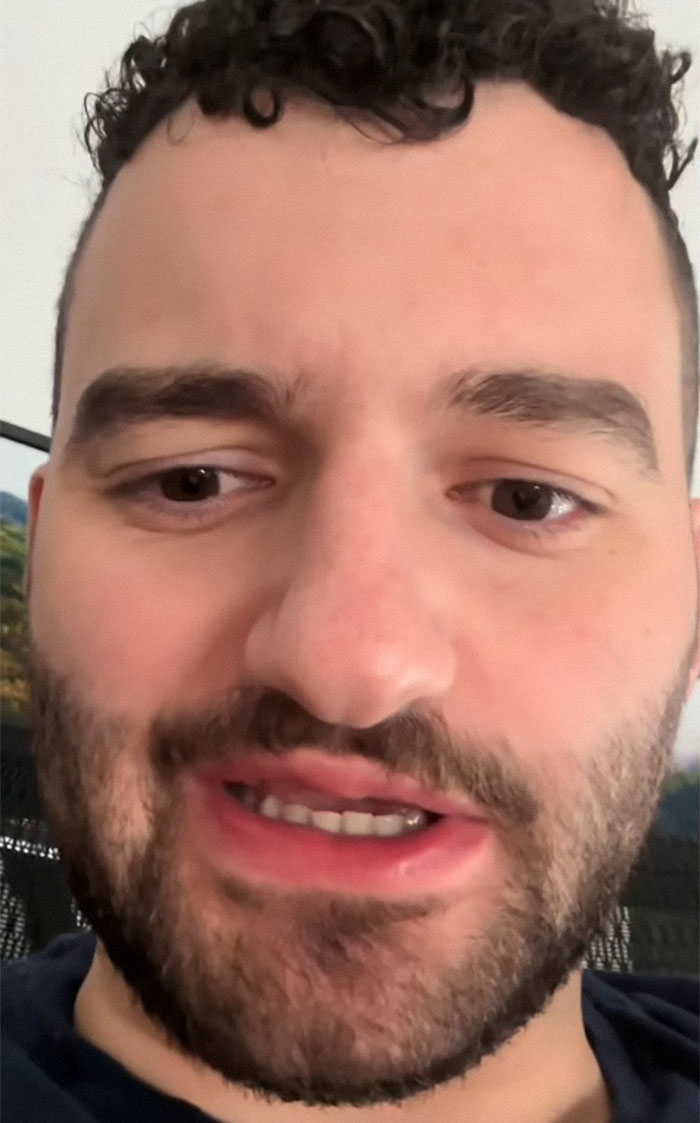 Close-up of a man with curly hair, discussing Airbnb guests taking out the trash.