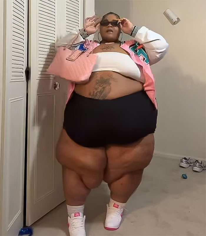 Plus size woman in casual outfit poses confidently in a room, showcasing fashion style.