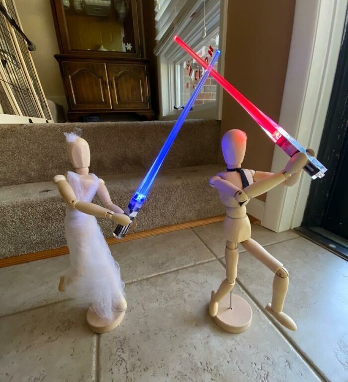 Wooden mannequins with blue and red lightsabers, posing for a quirky gift idea.