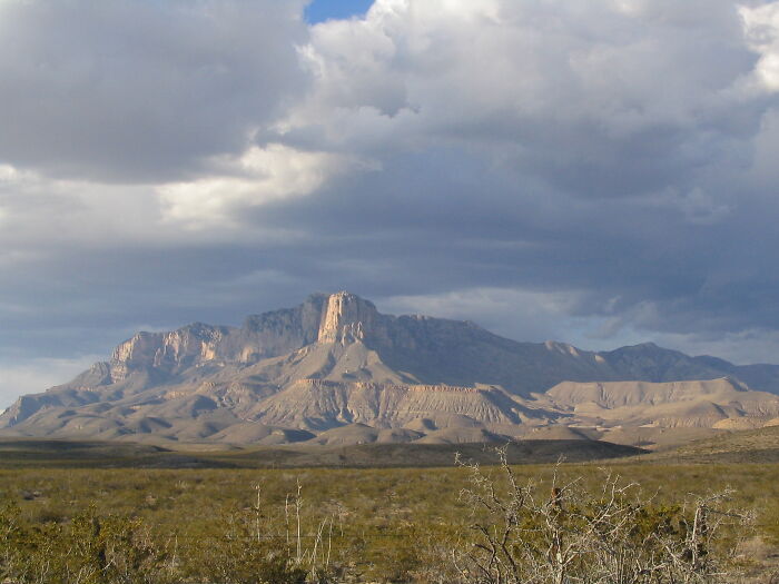 Expansive desert landscape with mountains under a cloudy sky, showcasing amazing views.