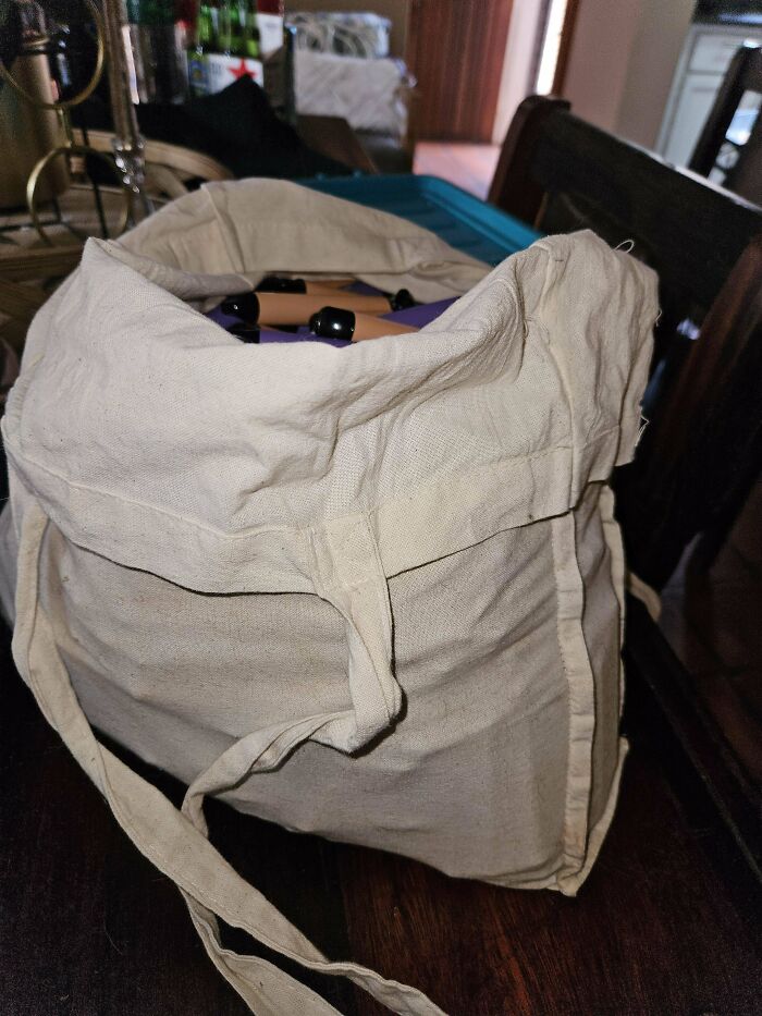 A canvas bag filled with bottles, highlighting themes of consumerism.