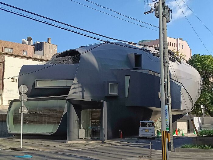 Modern bizarre building with unique futuristic design in an urban setting under a clear blue sky.