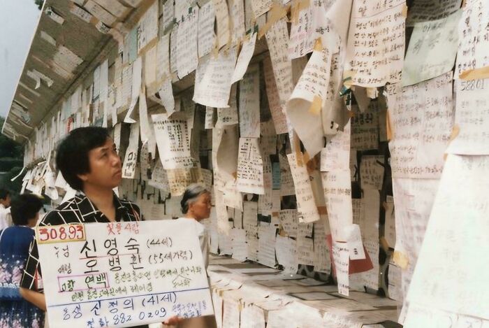 Person observing historical notices on a wall covered in handwritten papers.