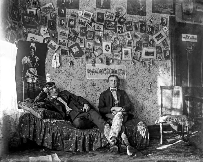 Two men in a vintage room surrounded by historical photos, capturing a fascinating glimpse into the past.