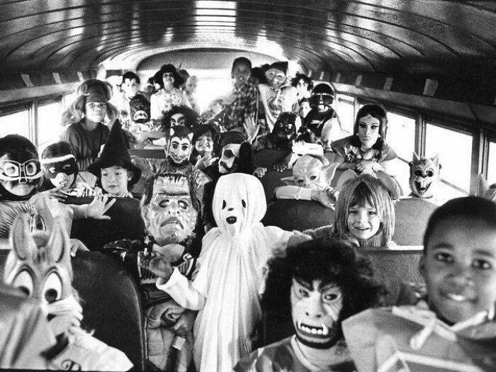 Children in Halloween costumes on a vintage school bus, capturing a fascinating historical moment.