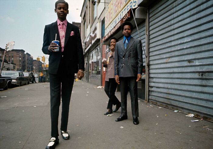 Three men in vintage suits stand confidently on an urban street, showcasing fascinating historical fashion.