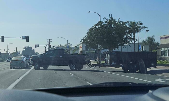 Truck blocking intersection with attached trailer on a sunny day, showcasing reckless driving behavior.