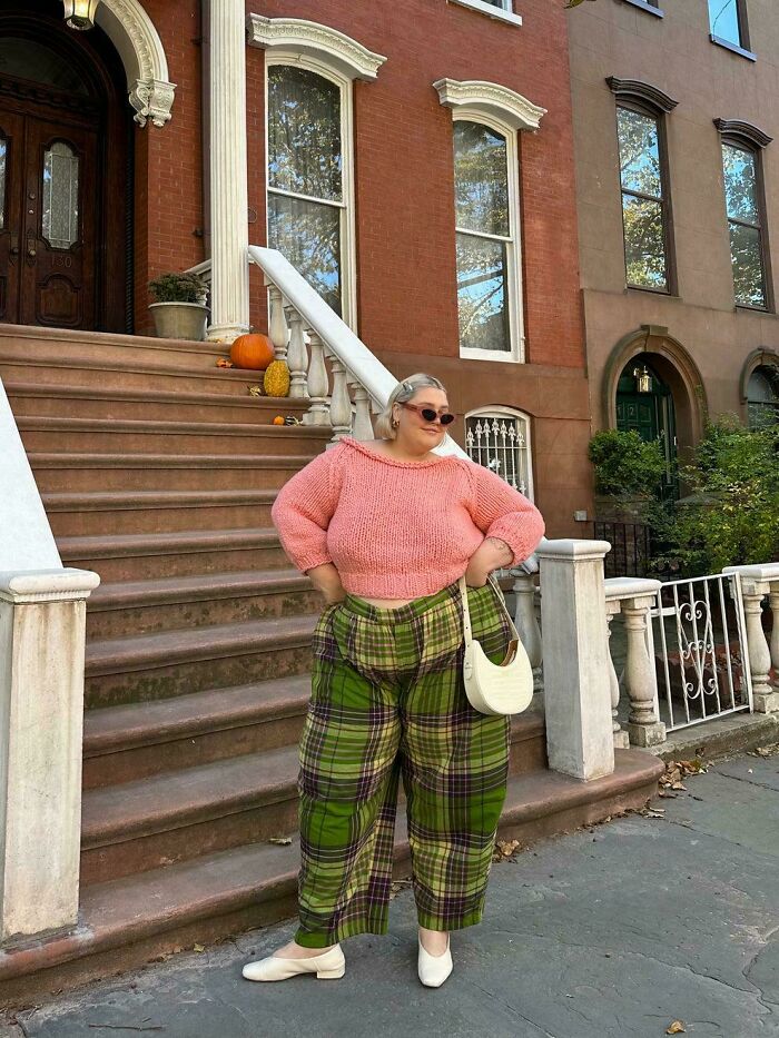 Person in pink sweater and plaid pants confidently posing outdoors, showcasing the contrast in Photoshop reality.